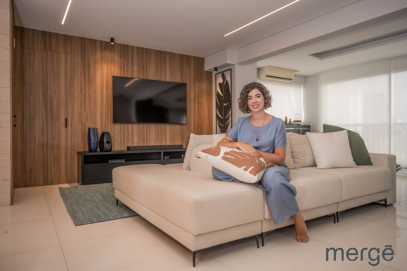 Marina Riva Destri sentada no sofá de uma sala de estar